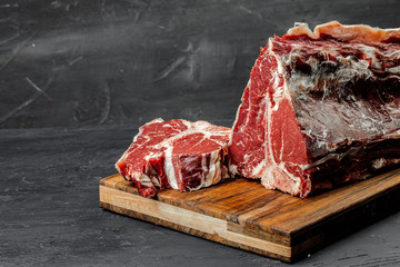 Raw T-bone steak cooking on stone table.