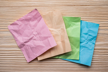 Several multi colored crumpled sheets of paper on a wooden surface.