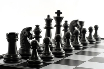 Black chess pieces on the chessboard on white background. Closeup of some chess figures. Chessmen isolated