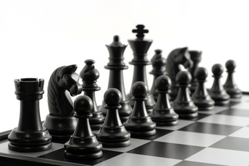 Black chess pieces on the chessboard on white background. Closeup of some chess figures. Chessmen...