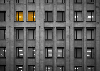 a gray office building with burning yellow Windows