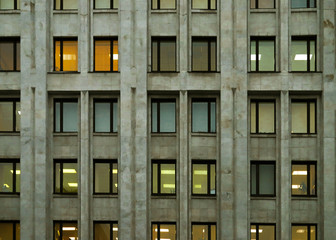 a gray office building with burning yellow Windows