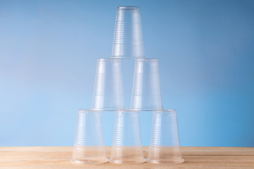 Unstable pyramid of empty plastic cups on a wooden table