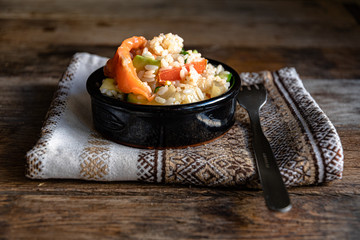 Poke salad in a black ceramic bowl with a kitchen napkin on a wooden table.