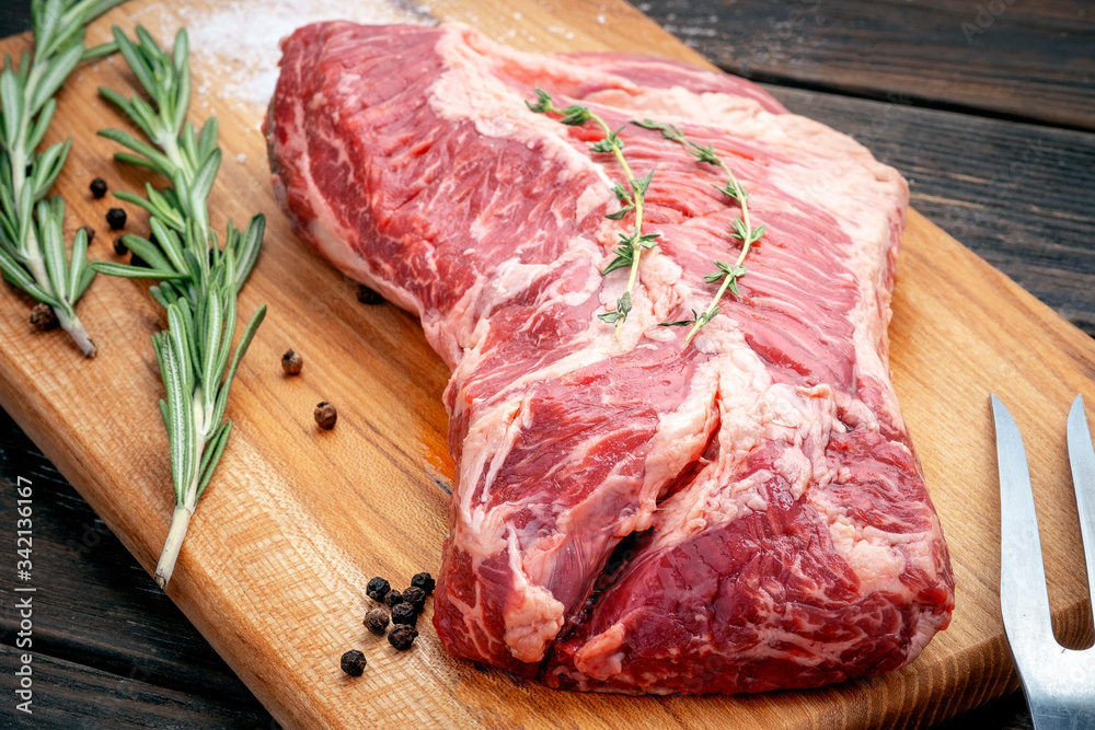 Wall mural Raw hanging tender or onglet steak of beef on wooden Board with rosemary and thyme on wooden background