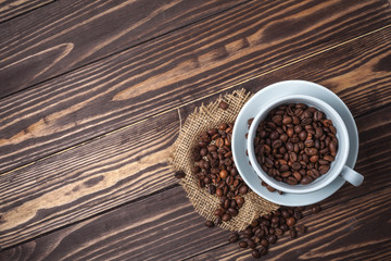 Coffee cup with coffee beans on a wooden tabletop. Top view