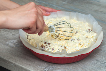 raw cottage cheese casserole dough in a round ceramic baking dish, female hands knead the dough