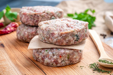Homemade raw minced meat cutlets of pork with spices and seasonings on a wooden Board