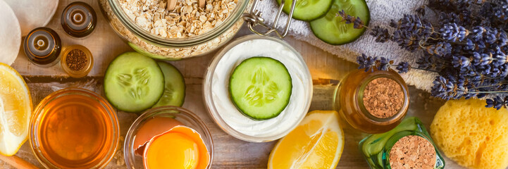 Concept of natural organic ingredients in cosmetology, home treatment in quarantine. Handmade mask with honey, egg, oat, lemon, cucumber, essential oils. Wooden background top view. Banner format
