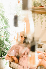 Creative portrait of a young girl who looks in camera throught the lamps. Beauty woman is relaxing on the soft sofa