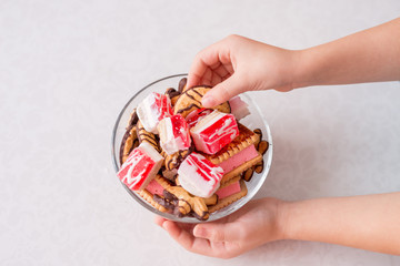 close-up of a child's hands taking sweets. Cookies and marmalade in a bowl on a white background