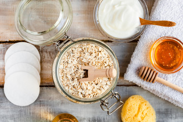 Concept of natural organic ingredients in cosmetology and gentle home treatment in quarantine. Do it yourselft. Handmade mask with oat, honey, yogurt. Wooden background. Flat lay top view close up