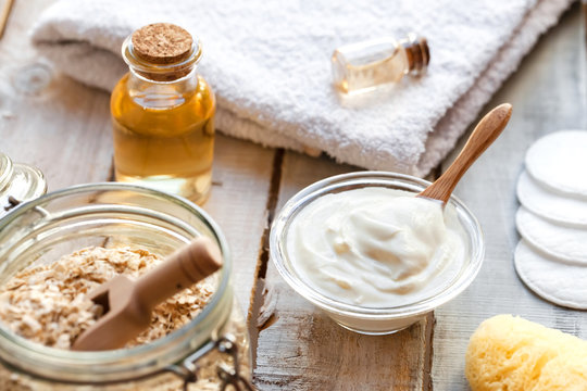 Concept of natural organic ingredients in cosmetology and gentle home treatment in quarantine. Do it yourselft. Handmade mask with oat, yogurt, oil. Wooden background, close up
