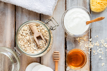 Concept of natural organic ingredients in cosmetics and gentle home treatment in quarantine. Do it yourselft. Handmade mask with oat, yogurt, honey. White wooden background, close up