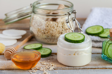Concept of natural organic ingredients in cosmetology, home treatment in quarantine. Do it yourselft. Handmade mask with honey, cucumber, oat yogurt, essential oil. Wooden background top view flat lay