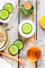 Concept of natural organic ingredients in cosmetology, home treatment in quarantine. Do it yourselft. Handmade mask with honey, oat, cucumber. Wooden background close up flat lay top view