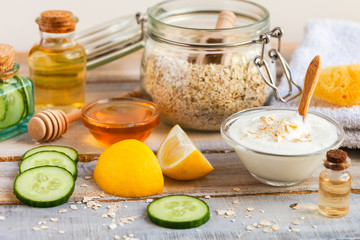 Concept of natural organic ingredients in cosmetology, home treatment in quarantine. Do it yourselft. Handmade mask with honey, egg, oat, lemon, cucumber, essential oils. Wooden background top view 