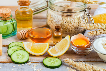 Concept of natural organic ingredients in cosmetology, home treatment during quarantine. Do it yourselft. Handmade mask with honey, egg, oat, lemon, cucumber, essential oils. Wooden background
