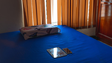 Room with a blue bed and cell phones