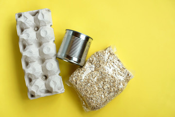 Food: eggs, canned food and oat groats on a yellow background