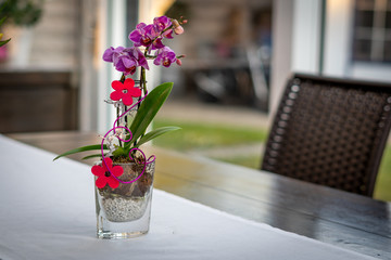 a table stands a flower arrangement with a purple orchid