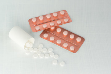 Scattered white and brown tablets in blisters on a white table. Pharmaceuticals for the treatment coronavirus