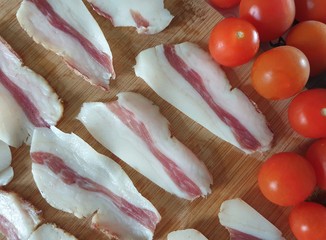 Sliced bacon and cherry tomatoes on a wooden board 