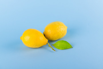 Two fresh yellow lemons on a blue pastel background, protection against coronavirus, viruses and infections, minimal immunity protection concept