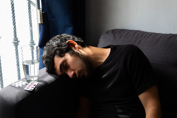 Young Hispanic man with a beard showing discomfort, pain, illness, suffering from coronavirus symptoms and confinement, concept of addictions, illness, medical treatment, pain, health care