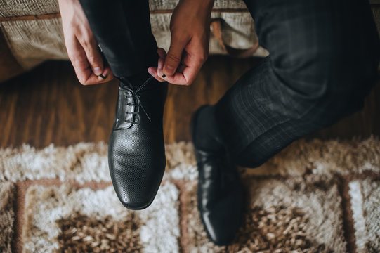 A man is tying shoelaces close-up on black leather shoes. Morning groom and businessman. Photography, concept.