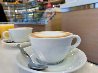Taza de cappucino sobre una mesa en el interior de una cafeteria