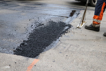 Worker using tool to smooth asphalt on driveway