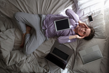woman trying to work being ill staying at home on bed with computer on the bed.