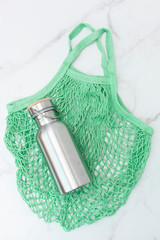top view of a green string bag and a bottle for water. Zero Waste Lifestyle, No Plastic