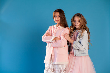 Portrait of two beautiful fashionable girlfriend girls in a white pink dress