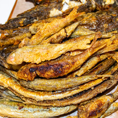 Fried small fish on wooden board