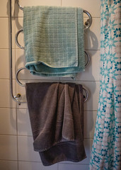 Two towels hanging on a towel rack in teal blue and white  bathroom