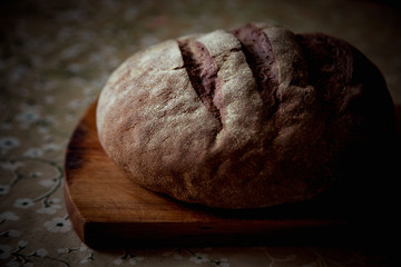 round bread, lying on a brown, wooden Board
