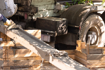 The concrete is poured on a wooden tray. As it merges down, the concrete splashes a lot of spray.