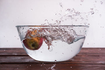 an Apple in water, an Apple in a spray of water in a glass transparent container, a wet Apple flying