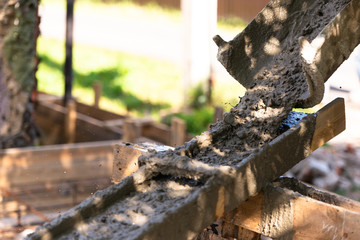 The concrete is poured on a wooden tray. As it merges down, the concrete splashes a lot of spray.