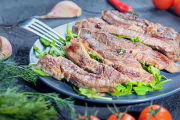 Sliced freshly cooked steak closeup. Tasty meat with arugula and vegetables.