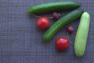 
Cucumbers, radishes pink and red tomatoes on the kitchen table. View from above