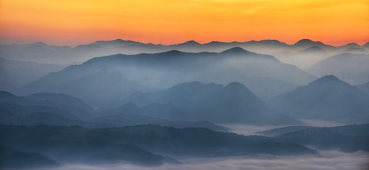 Naklejka na ściany i meble silhouettes of foggy mountains. picturesque mountain peaks at sunrise.