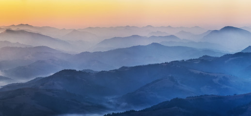 Naklejka na ściany i meble silhouettes of foggy mountains. picturesque mountain peaks at sunrise.