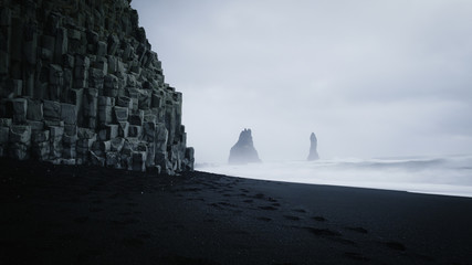 Reynisfjara schwarzer Sandstrand &amp  Reynisdrangar bei dunklem und launischem Wetter, Island