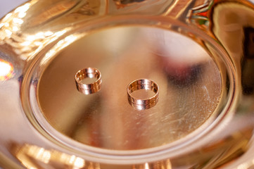 Pair of gold wedding rings on the golden plate