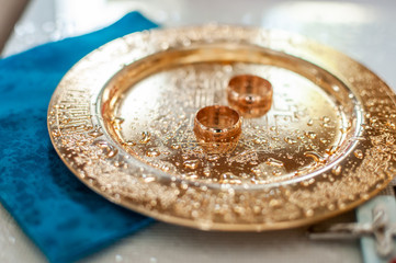 Pair of gold wedding rings on the golden plate