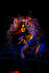 Fototapeta premium The girl who plays the role of a Ghost or spirit in the theater is sitting between the rows of chairs