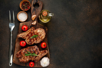 Fototapeta na wymiar two grilled beef steaks with spices on a stone background with copy space for your text